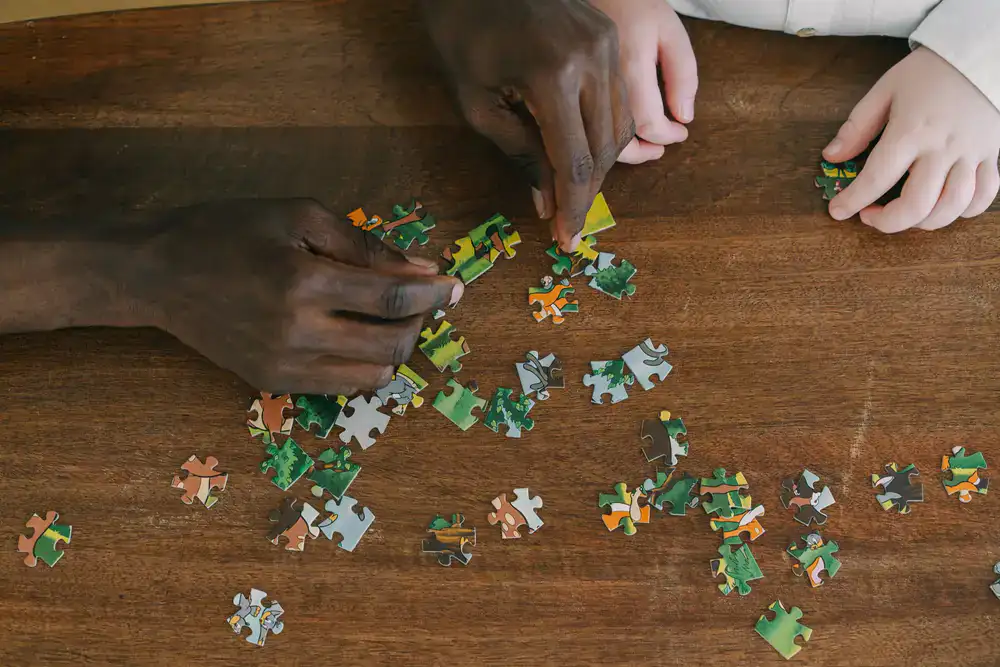 Close up of hands sorting jigsaw puzzle pieces on a wooden table